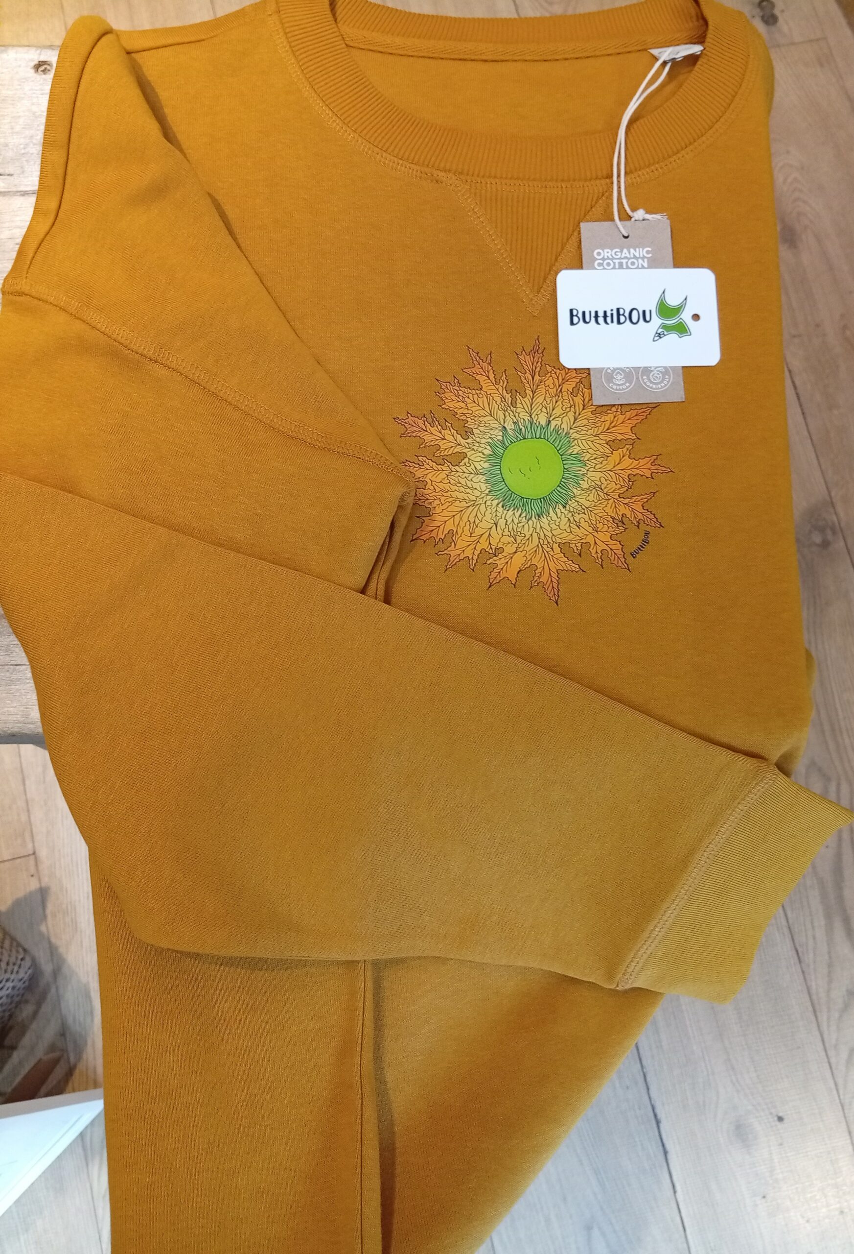 Sudadera oversize color mostaza de algodón orgánico con el eguzkilore estampado como un medallón. Diseño exclusivo de ButtiBou Pamplona inspirado en la tradición navarra.    Mustard oversized organic cotton sweatshirt with the eguzkilore printed as a medallion. Exclusive design by ButtiBou Pamplona inspired by Navarre tradition. Sudadera oversize color mostaza de algodón orgánico con eguzkilore estampado como un medallón de ButtiBou Pamplona. Mustard oversized organic cotton sweatshirt with eguzkilore printed as a medallion by ButtiBou Pamplona