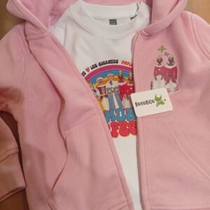 Sudadera infantil rosa con cremallera y capucha junto a camiseta blanca de manga corta con el mismo diseño “Gigantes en armonía” de ButtiBou Pamplona. Pink children’s zip-up hoodie with hood and white short-sleeve t-shirt featuring the same “Giants in Harmony” design by ButtiBou Pamplona.